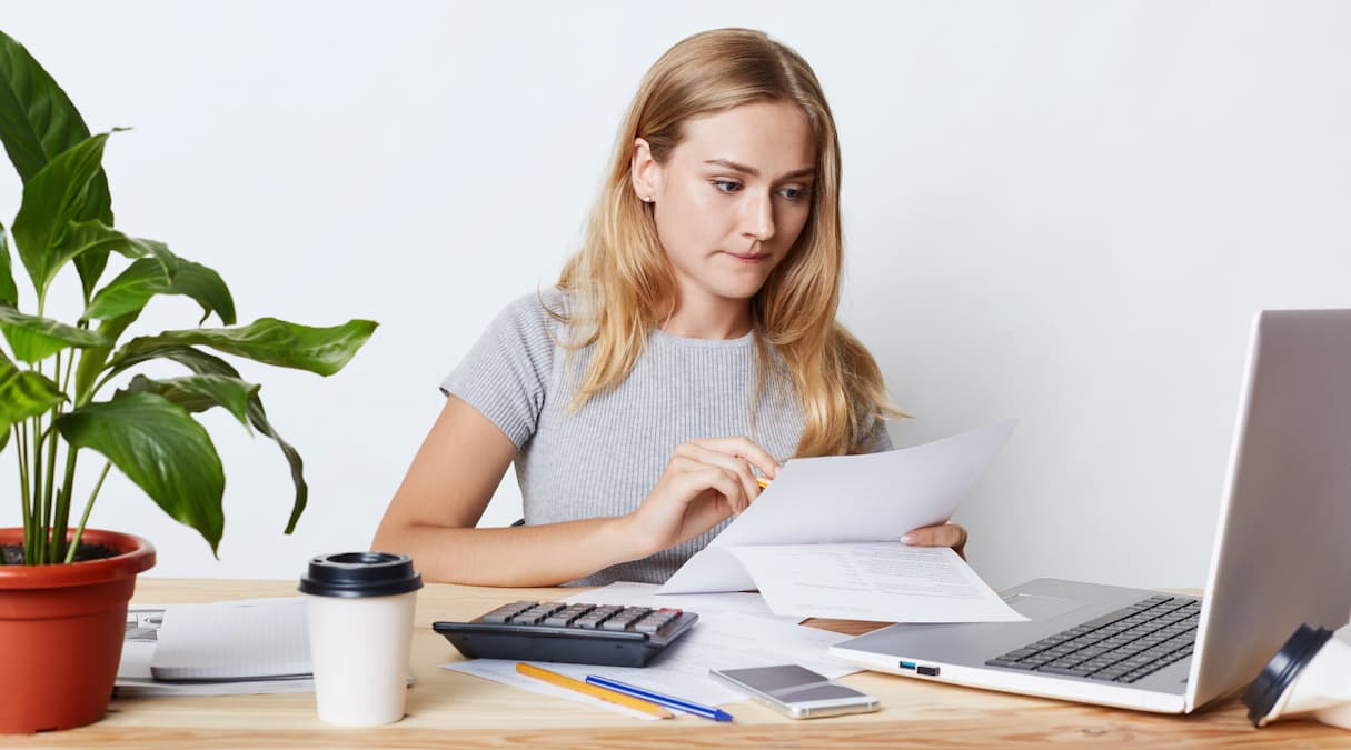Uma mulher lojista sentada em sua mesa de trabalho e aprendendo a como calcular o frete online do seu e-commerce e loja virtual||calcular o frete